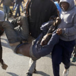 
              Community members carry in illegal gold miner to surrender him to police near Krugersdorp, South Africa, Thursday, Aug. 4, 2022. Community members beat suspected illegal miners with sticks and set fire to their camps following the alleged gang rapes of eight women by miners last week. (AP Photo/Denis Farrell)
            