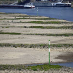 
              A cargo ship sails past dry land on the Rhine, in Dusseldorf, North Rhine-Westphalia, Germany. After weeks of drought, the water levels of the Rhine have reached historic lows. (Federico Gambarini/dpa via AP)
            