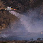A helicopter drops water on a wildfire in Castaic, Calif. on Wednesday, Aug. 31, 2022. (AP Photo/Ringo H.W. Chiu)