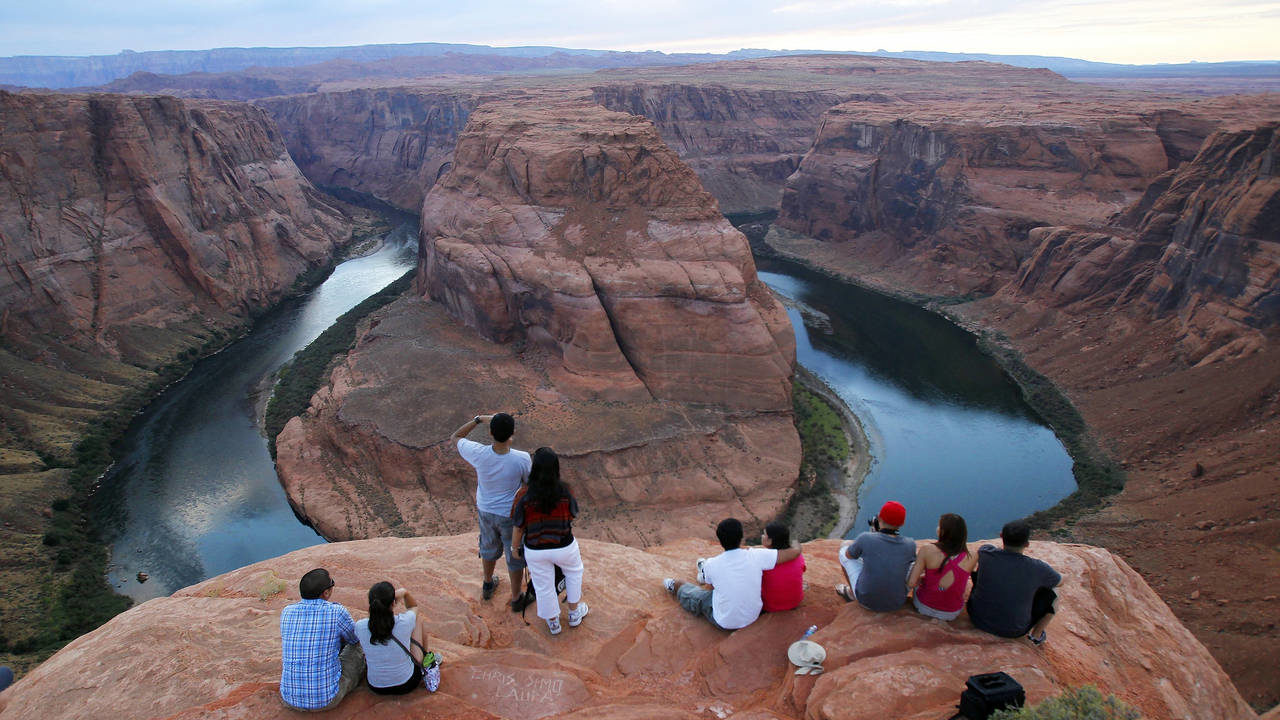 FILE - Visitors view the dramatic bend in the Colorado River at the popular Horseshoe Bend in Glen ...