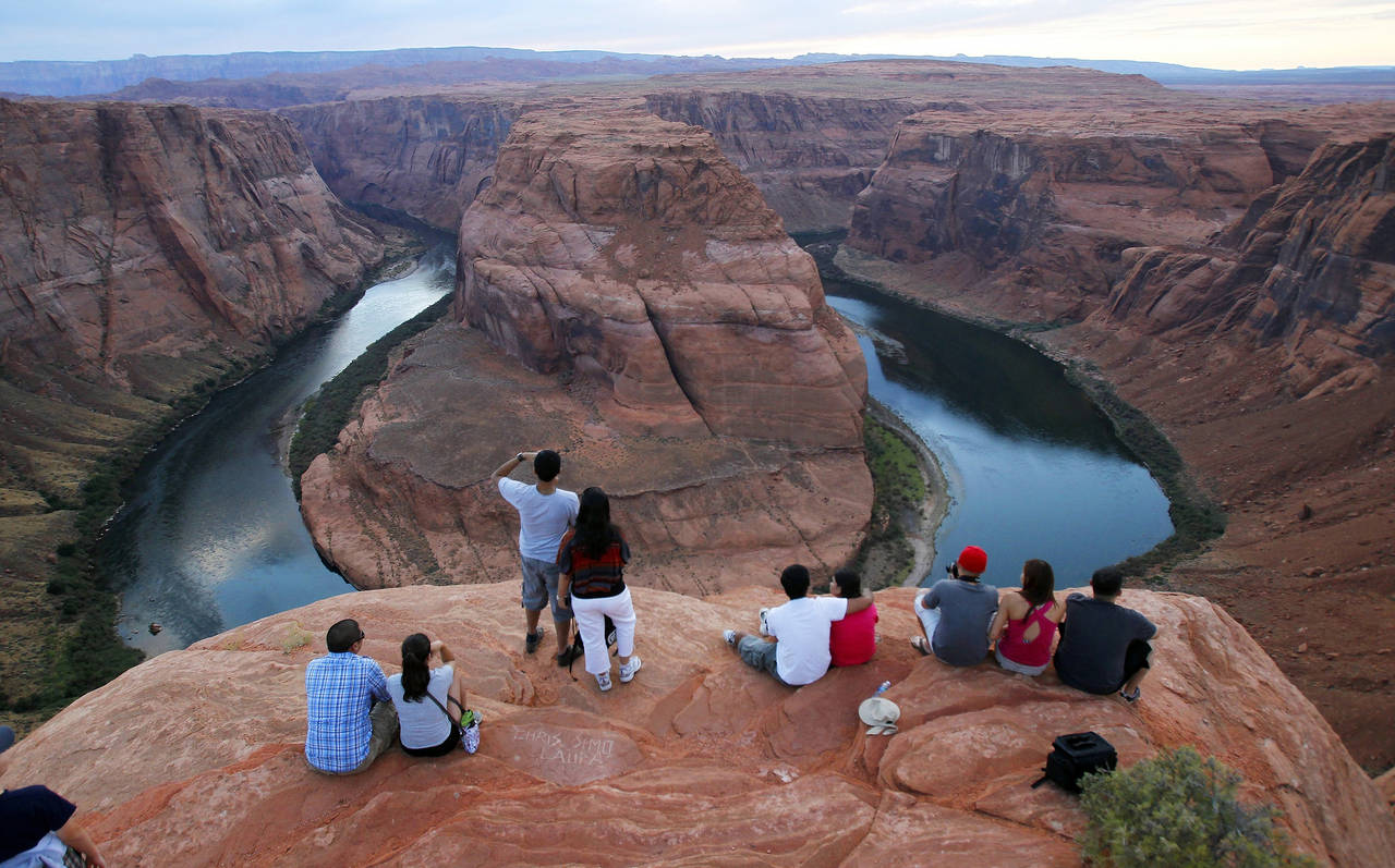 FILE - Visitors view the dramatic bend in the Colorado River at the popular Horseshoe Bend in Glen ...