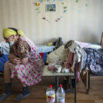 
              Vera Vasiukova, 71, left, sits on her bed at a center for displaced people near Mykolaiv, Ukraine, Tuesday, Aug. 9, 2022. Vera's house was destroyed by Russian attacks in Snigurivka village, Mykolaiv region. Many people like Vera are unable return home because of the continuing fighting. (AP Photo/Evgeniy Maloletka)
            