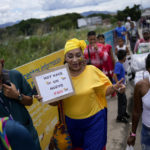 
              A supporters of Colombia's new President Gustavo Petro carrying a sign reading in Spanish "A new country is born today" crosses the border from Colombia to Venezuela in San Antonio, Venezuela, Sunday, Aug. 7, 2022. Colombia's incoming foreign minister and his Venezuelan counterpart announced in late July that the border, partially closed since 2015, will gradually reopen after the two nations restore diplomatic ties when Colombia's new president is sworn-in on Aug. 7. (AP Photo/Matias Delacroix)
            