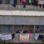 
              Young children play up for the camera from the balcony of where they live in the Kibera area of Nairobi, Kenya Friday, Aug. 12, 2022. Vote-tallying in Kenya's close presidential election isn't moving fast enough, the electoral commission chair said Friday. (AP Photo/Ben Curtis)
            
