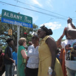 
              Wanda Cooper-Jones (on right in yellow dress) poses for photos with supporters beneath a new street sign honoring her son, Ahmaud Arbery, that was unveiled Tuesday, Aug. 9, 2022, in Brunswick, Ga. City officials approved the honor for Arbery, a 25-year-old Black man who was fatally shot in February 2020 after being chased by three white men in pickup trucks who spotted him running in their neighborhood. All three men were later convicted of murder and federal hate crimes. (AP Photo/Russ Bynum)
            