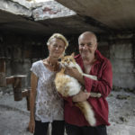 
              Zhanna Dynaeva and Serhiy Dynaev stand with a cat inside their house which was destroyed by Russian bombardment, in the village of Novoselivka, near Chernihiv, Ukraine, Saturday, Aug. 13, 2022. Residents in many heavily-damaged areas in Ukraine have set up their own initiatives to rebuild homes before the winter as international organizations rush aid to Ukraine to help with the reconstruction effort. (AP Photo/Evgeniy Maloletka)
            