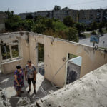 
              Widow Liudmyla Shyshkina, 74, and her son Pavlo Shyshkin, 46, stand at their apartments house, which was destroyed after Russian bombardment of residential area in Nikopol, Ukraine, on Monday, Aug, 22, 2022. In Nikopol, across the river from Ukraine's main nuclear power plant, Russian shelling wounded four people Monday, an official said. The city on the Dnipro River has faced relentless pounding since July 12 that has damaged some 850 buildings and sent about half its population of 100,000 fleeing. (AP Photo/Evgeniy Maloletka)
            