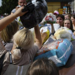 
              Local residents, many of whom fled the war, gather to hand out donated items such as medicines, clothes, and personal belongings to their relatives on the territories occupied by Russia, in Zaporizhzhia, Ukraine, Sunday, Aug. 14, 2022. Volunteers transport these items across the frontline and distribute them to addresses at their own risk. (AP Photo/Andriy Andriyenko)
            