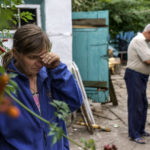 
              Nina Bilyk, left, wipes away tears Saturday, Aug. 13, 2022, while standing where her partner, Ivan Fartukh, the cousin of Andrii Fartukh, right, was killed in a Russian rocket attack last night at their home in Kramatorsk, Donetsk region, eastern Ukraine. The strike killed three people and wounded 13 others, according to the mayor. The attack came less than a day after 11 other rockets were fired at the city. (AP Photo/David Goldman)
            