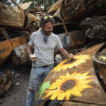 
              American artist Trek Thunder Kelly paints sunflowers on cars which were destroyed by Russian attacks in Irpin, on the outskirts of Kyiv, Ukraine, on Friday, Aug. 12, 2022. Kelly came to Ukraine as a volunteer to paint cars, the destroyed Palace of Culture and school basements for the project "Flowers For Hope" which aims to provide a distraction in environments devastated by war and raise money for humanitarian aid.(AP Photo/Evgeniy Maloletka)
            