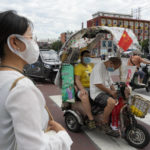 
              A man and a child wearing masks sit in an electric tricycle with a Chinese national flag in Beijing, Monday, Aug. 15, 2022. China’s central bank trimmed a key interest rate Monday to shore up sagging economic growth at a politically sensitive time when President Xi Jinping is believed to be trying to extend his hold on power. (AP Photo/Ng Han Guan)
            