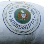 A water tower emblazon with the City of Jackson, Miss., official seal looms over this north Jackson neighborhood Wednesday, Aug. 31, 2022. The recent flood worsened Jackson's longstanding water system problems and the state Health Department has had Mississippi's capital city under a boil-water notice since late July. (AP Photo/Rogelio V. Solis)