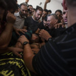 
              Mourners react next to the body of Palestinian Tamim Hijazi, who was killed in an Israeli air strike, during his funeral in Khan Yunis in the southern Gaza Strip, Saturday, Aug. 6, 2022. Israeli jets pounded militant targets in Gaza as rockets rained on southern Israel, hours after a wave of Israeli airstrikes on the coastal enclave killed at least 11 people, including a senior militant and a 5-year-old girl. The fighting began with Israel's dramatic targeted killing of a senior commander of the Palestinian Islamic Jihad continued into the morning Saturday, drawing the sides closer to an all-out war. (AP Photo/Yousef Masoud)
            