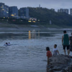 
              People stand on a rocky outcropping normally submerged in the channel of the Yangtze River in southwestern China's Chongqing Municipality, Friday, Aug. 19, 2022. Ships crept down the middle of the Yangtze on Friday after the driest summer in six decades left one of the mightiest rivers shrunk to barely half its normal width and set off a scramble to contain damage to a weak economy in a politically sensitive year. (AP Photo/Mark Schiefelbein)
            