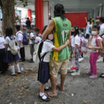 
              A girl holds on to his father during the opening of classes at the San Juan Elementary School in Pasig, Philippines on Monday, Aug. 22, 2022. Millions of students wearing face masks streamed back to grade and high schools across the Philippines Monday in their first in-person classes after two years of coronavirus lockdowns that are feared to have worsened one of the world's most alarming illiteracy rates among children. (AP Photo/Aaron Favila)
            