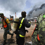 
              A Cuban firefighter stands between Mexican soldiers as they work to put out a deadly fire at a large oil storage facility in Matanzas, Cuba, Tuesday, Aug. 9, 2022. The fire was triggered when lighting struck one of the facility's eight tanks late Friday, Aug. 5th. (Yamil Lage, Pool photo via AP)
            