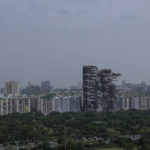 
              Explosives are detonated to demolish twin high-rise apartment towers in Noida, outskirts of New Delhi, India, Sunday, Aug. 28, 2022. The demolition was done after the country's top court declared them illegal for violating building norms. The 32-story and 29-story towers, constructed by a private builder were yet to be occupied and became India's tallest structures to be razed to the ground. (AP Photo/Altaf Qadri)
            