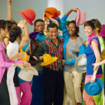 
              FILE - Models in colorful clothes surround Japanese designer Issey Miyake after the presentation of his "1994 Spring-Summer ready-to-wear collection" presented in Paris, Oct. 8, 1993. Miyake, who built one of Japan’s biggest fashion brands and was known for his boldly sculpted pleated pieces as well as former Apple CEO Steve Jobs’ black turtlenecks, has died. He was 84. He died Aug. 5, 2022, of liver cancer, Miyake Design Office said Tuesday, Aug. 9. (AP Photo/Lionel Cironneau, File)
            
