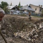 
              Workers clear debris next to a crater caused by a rocket strike on a house in Kramatorsk, Donetsk region, eastern Ukraine, Friday, Aug. 12, 2022. There were no injuries reported in the strike. (AP Photo/David Goldman)
            
