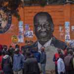 
              Residents gather to discuss the election in front of a mural of presidential candidate Raila Odinga, in the Kibera area of Nairobi, Kenya Thursday, Aug. 11, 2022. Kenyans are waiting for the results of a close presidential election in which the turnout was lower than usual. (AP Photo/Ben Curtis)
            