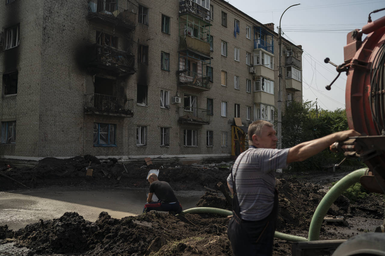 Workers drain water from a crater created by an explosion that damaged a residential building after...