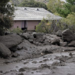 
              The front yard of a property is covered in mud in the aftermath of a mudslide Tuesday, Sept. 13, 2022, in Oak Glen, Calif. Cleanup efforts and damage assessments are underway east of Los Angeles after heavy rains unleashed mudslides in a mountain area scorched by a wildfire two years ago. (AP Photo/Marcio Jose Sanchez)
            