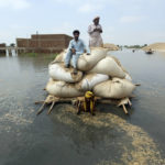 
              Victims of the unprecedented flooding from monsoon rains use makeshift barge to carry hay for cattle, in Jaffarabad, a district of Pakistan's southwestern Baluchistan province, Monday, Sept. 5, 2022. The U.N. refugee agency rushed in more desperately needed aid Monday to flood-stricken Pakistan as the nation's prime minister traveled to the south where rising waters of Lake Manchar pose a new threat. (AP Photo/Fareed Khan)
            
