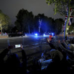 
              Members of the public wave to Britain's King Charles III, as they as they secure their positions on the Mall in London, Sunday, Sept. 18, 2022, ahead of the funeral of Queen Elizabeth II on Monday. (David Davies/PA via AP)
            