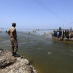 
              Soldiers survey the flood waters as victims wait to receive relief aid from the Pakistani Army in the Qambar Shahdadkot district of Sindh Province, Pakistan, Friday, Sept. 9, 2022. U.N. Secretary-General Antonio Guterres appealed to the world for help for cash-strapped Pakistan after arriving in the country Friday to see the climate-induced devastation from months of deadly record floods. (AP Photo/Fareed Khan)
            