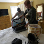 
              CORRECTS TO FLORIDA FISH AND WILDLIFE CONSERVATION COMMISSION NOT FLORIDA FISH AND WILDLIFE SERVICE - Clay Wagner, of Florida Fish and Wildlife Conservation Commission, assists Bobby Stillwell with his luggage, as FWC officials help Stillwell and his wife evacuate from a third-story beachfront condo, after Hurricane Ian tore through about one week into the couple's planned three month vacation, in Fort Myers Beach, Fla., Friday, Sept. 30, 2022. (AP Photo/Rebecca Blackwell)
            