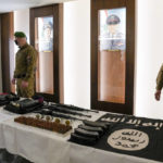 FILE- Lebanese police special forces stand next to a table where an Islamist State group flag, explosive belts, various weapons and explosives confiscated by police intelligence from Islamic State group suspects are displayed, during a press conference at the Lebanese police headquarters in Beirut, Lebanon, Feb. 23, 2022. A newly declassified U.S. intelligence report predicted in 2020 that the Islamic State group was likely to regain much of its former strength and global influence, particularly if American and Western forces reduced their role in countering the extremist movement. (AP Photo/Hassan Ammar, File)