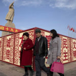 
              FILE - Residents walk past a statue of the late Chinese leader Mao Zedong near billboards reading "Welcome 19th Congress" "Patriotism" and "Democracy" near a square in Kashgar in western China's Xinjiang region on Nov. 4, 2017. China has responded furiously to a United Nations report on alleged human rights abuses in its northwestern Xinjiang region targeting Uyghurs and other mainly Muslim ethnic minorities. (AP Photo/Ng Han Guan, File)
            
