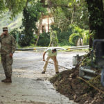 
              National Guards stand to direct traffic as resident Luis Noguera helps clear the road affected by Hurricane Fiona in Cayey, Puerto Rico, Tuesday, Sept. 20, 2022. Fiona triggered a blackout when it hit Puerto Rico’s southwest corner on Sunday. (AP Photo/Stephanie Rojas)
            