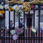 
              Flowers are attached to the gate of Buckingham Palace in London, Friday, Sept. 9, 2022. Queen Elizabeth II, Britain's longest-reigning monarch and a rock of stability across much of a turbulent century, died Thursday Sept. 8, 2022, after 70 years on the throne. She was 96. (AP Photo/Kirsty Wigglesworth)
            