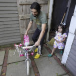 Mohammad Walizada, left, who fled Afghanistan with his family, assists his daughter Hasnat, 3, with a bicycle at their home in Epping, N.H., Thursday, Sept. 15, 2022. Since the U.S. military's withdrawal from Kabul last year, the Sponsor Circle Program for Afghans has helped over 600 Afghans restart their lives in their communities. (AP Photo/Steven Senne)
