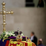 
              A view of Queen Elizabeth's coffin, draped in the Royal Standard, with the Imperial State Crown and the Sovereign's orb and sceptre, and flowers on top, following her death, during her lying in state at Westminster Hall, in Westminster Palace, in London, Sunday, Sept. 18, 2022. (Sarah Meyssonnier/Pool Photo via AP)
            