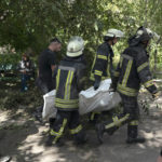 
              Firefighters carry a bag containing the body of a person killed after a Russian attack which heavily damaged a residential building in Sloviansk, Ukraine, Wednesday, Sept. 7, 2022. (AP Photo/Leo Correa)
            