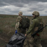 
              Ukrainian national guard servicemen carry a bag containing the body of a Ukrainian soldier in an area near the border with Russia, in Kharkiv region, Ukraine, Monday, Sept. 19, 2022. In this operation seven bodies of Ukrainian soldiers were recovered from what was the battlefield in recent months. (AP Photo/Leo Correa)
            