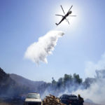 
              A helicopter drops water over a flareup alongside the Barrett Mobile Home and RV Park while fighting the Border Fire, Thursday, Sept. 1, 2022, in Dulzura, Calif. California wildfires chewed through rural areas north of Los Angeles and east of San Diego on Thursday, racing through bone-dry brush and prompting evacuations as the state sweltered under a heat wave that could last through Labor Day. (AP Photo/Gregory Bull)
            