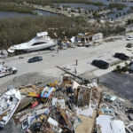 
              In this photo taken by a drone, the two-story Getaway Marina building, front, lies reduced to rubble as displaced boats rest along the roadside and a trailer park, at top, lies nearly devoid of homes, following the passage of Hurricane Ian, on San Carlos Boulevard in Fort Myers Beach, Fla., Thursday, Sept. 29, 2022. (AP Photo/Rebecca Blackwell)
            