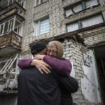 
              Yevdokia, 65, hugs her son Alexander in front of their house, which was heavily damaged by Russia attack, in the recently retaken area of Izium, Ukraine, Wednesday, Sept. 14, 2022. (AP Photo/Evgeniy Maloletka)
            