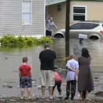 
              Residents check on one another in a flooded neighborhood in the aftermath of Hurricane Ian, Thursday, Sept. 29, 2022, in Orlando, Fla. (AP Photo/Phelan M. Ebenhack)
            