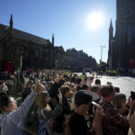 
              People take photos with their mobile phones along route prior to the departure of the hearse carrying Queen Elizabeth's coffin from St Giles Cathedral to Edinburgh Airport in Edinburgh, Scotland, Tuesday, Sept. 13, 2022. After lying in the cathedral most of Tuesday, the queen's coffin will be flown back to London and driven to her official London home, Buckingham Palace. (AP Photo/Jon Super)
            