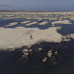 Olof Wood walks across reef-like structures called microbialites, exposed by receding waters at the Great Salt Lake Tuesday, Sept. 6, 2022, near Salt Lake City. A blistering heat wave is breaking records in Utah, where temperatures hit 105 degrees Fahrenheit (40.5 degrees Celsius) on Tuesday. That is the hottest September day recorded going back to 1874. (AP Photo/Rick Bowmer)
