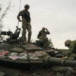 
              Ukrainian servicemen stand atop a destroyed Russian tank in a retaken area near the border with Russia in Kharkiv region, Ukraine, Saturday, Sept. 17, 2022. (AP Photo/Leo Correa)
            