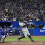
              New York Yankees' Aaron Judge hits a two-run home run, his 61st homer of the season, next to Toronto Blue Jays catcher Danny Jansen during the seventh inning of a baseball game Wednesday, Sept. 28, 2022, in Toronto. (Nathan Denette/The Canadian Press via AP)
            