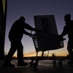 
              FILE - People transport a television to their car after shopping at a Best Buy store, Nov. 26, 2021, in Overland Park, Kan. A stronger dollar helps U.S. shoppers by keeping a lid on prices for imports and pushing downward on inflation. (AP Photo/Charlie Riedel, File)
            