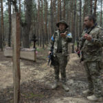 
              Oleg Kotenko, the Commissioner for Issues of Missing Persons under Special Circumstances, left, speaks to his comrade near the unidentified graves of civilians and Ukrainian soldiers in the recently retaken area of Izium, Ukraine, Thursday, Sept. 15, 2022 who had been killed by Russian forces near the beginning of the war. A mass grave of Ukrainian soldiers and unknown buried civilians was found in the forest of recently recaptured city of Izium. (AP Photo/Evgeniy Maloletka)
            