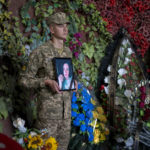 
              A Ukrainian soldier holds a photo of Olga Simonova, 34, a Russian woman who was killed in the Donetsk region while fighting on Ukraine's side in the war with her native country, in a crematorium in Kyiv, Ukraine, Friday, Sept. 16, 2022. (AP Photo/Roman Hrytsyna)
            