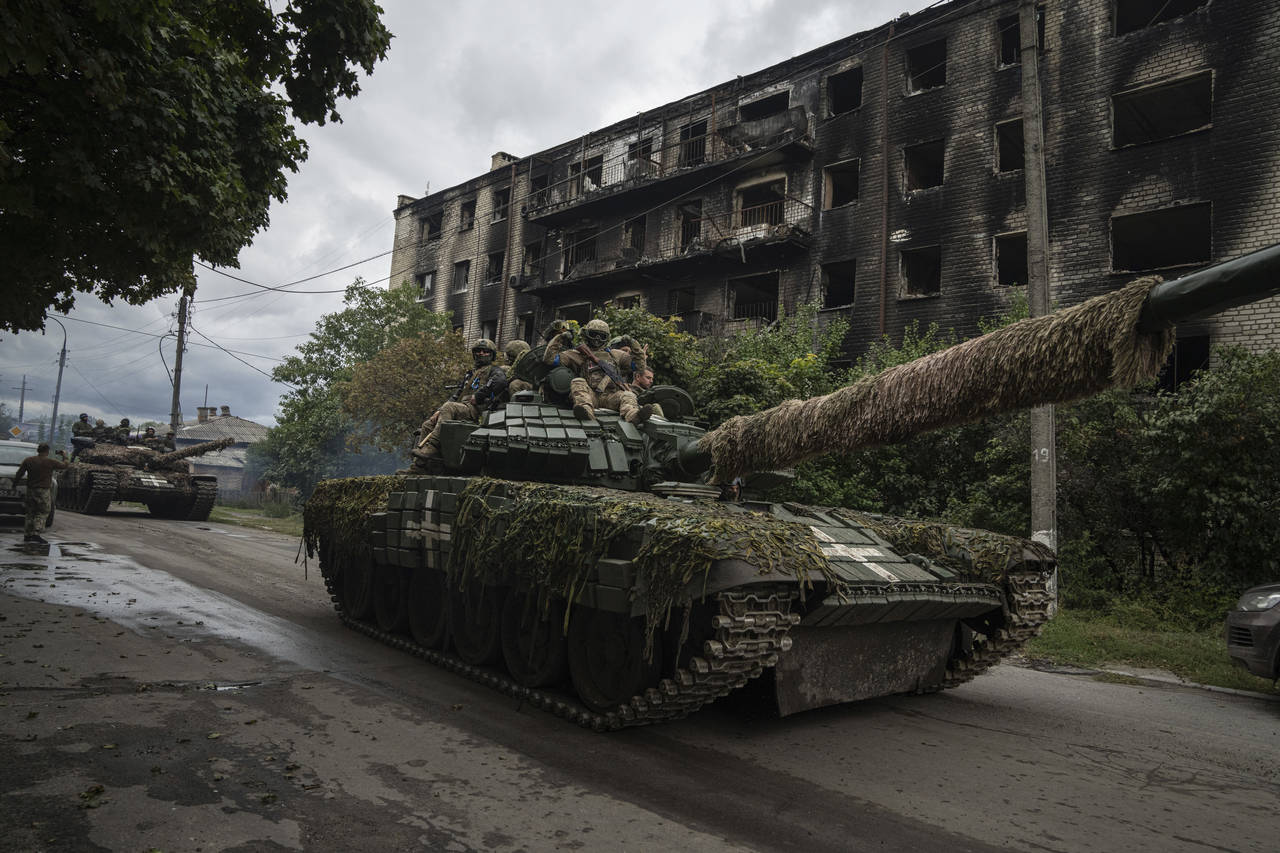 Ukrainian servicemen drive atop a tank in the recently retaken area of Izium, Ukraine, Wednesday, S...